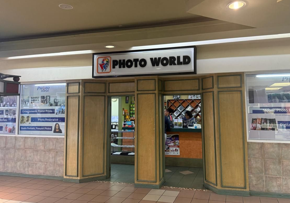 Photo World store entrance with sign, display windows, and closed wooden doors.