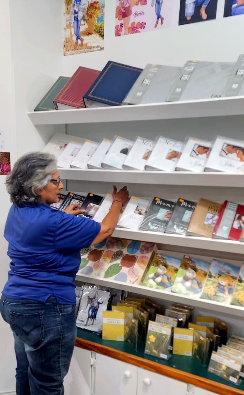 Woman in blue shirt and jeans arranging items on shelves in a store.