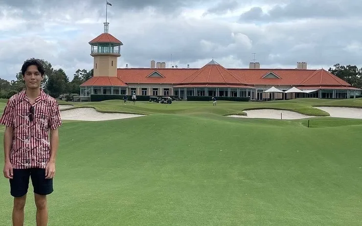 a man is standing in front of a large building on a golf course .