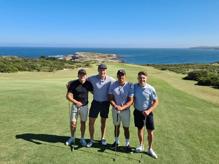 a group of men are posing for a picture on a golf course .