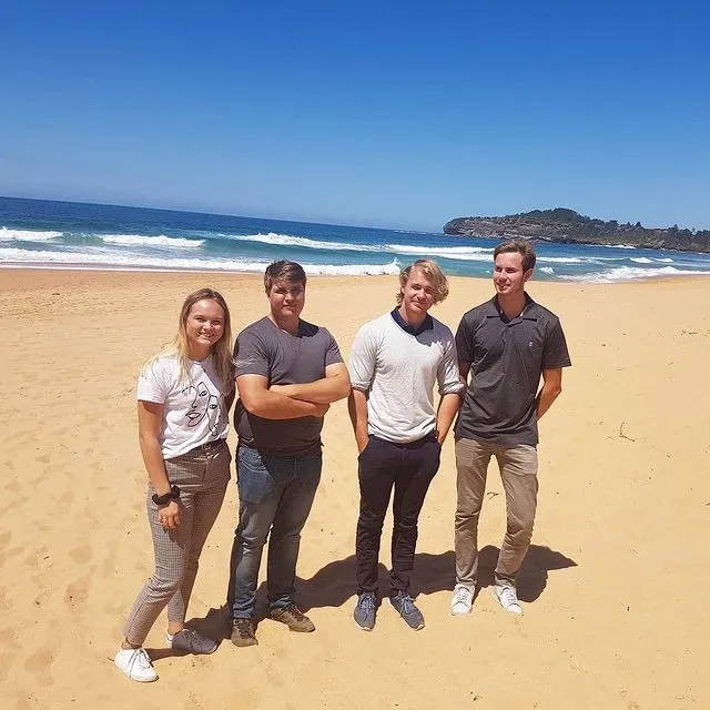 a group of people are posing for a picture on a beach
