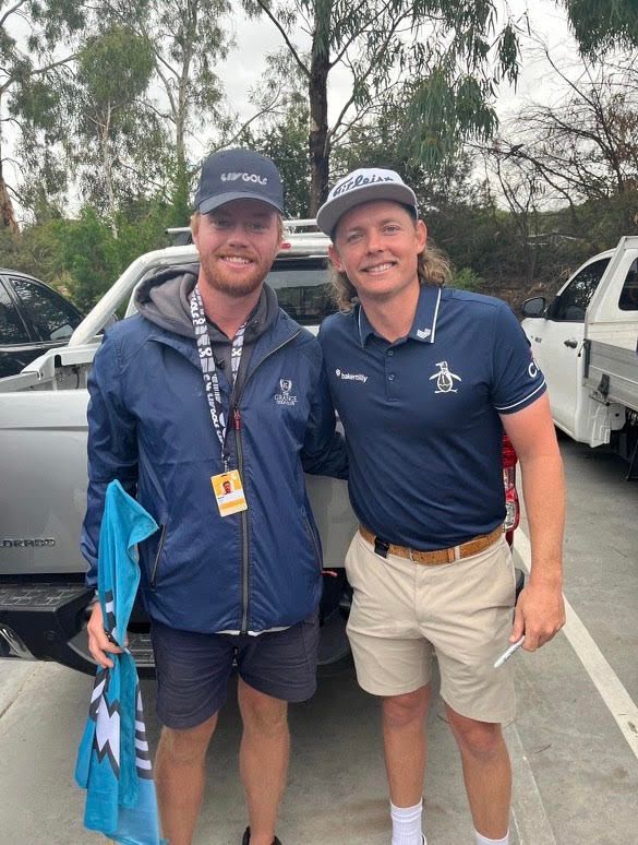 two men are posing for a picture in a parking lot