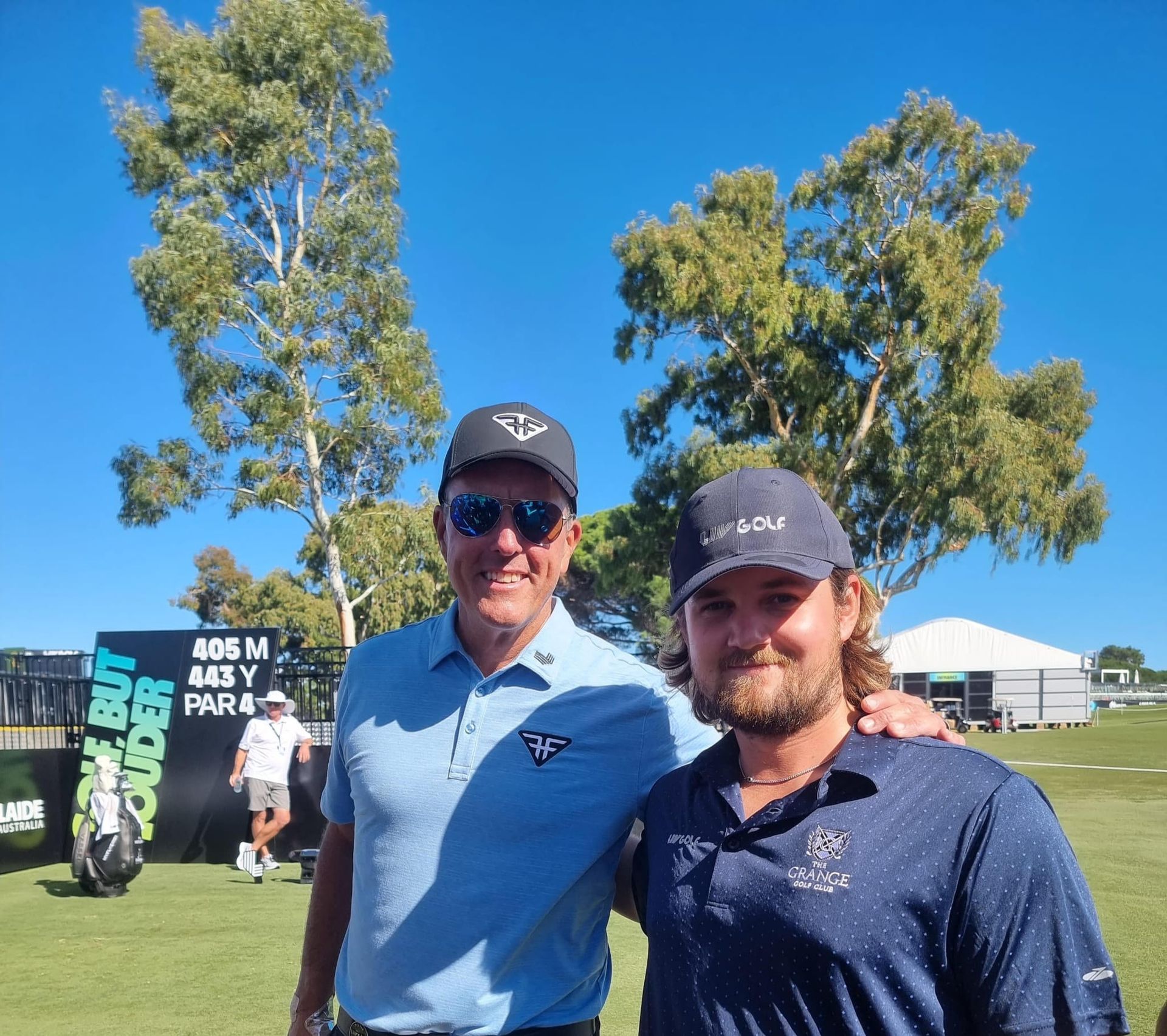 two men are posing for a picture on a golf course