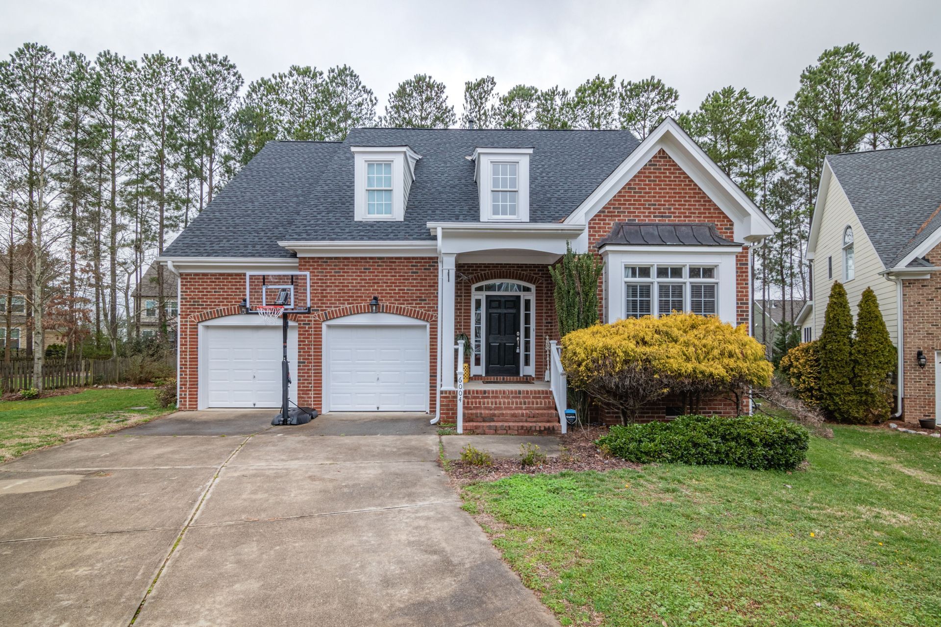 Brick house with two-car garage, front porch, and driveway in a suburban neighborhood