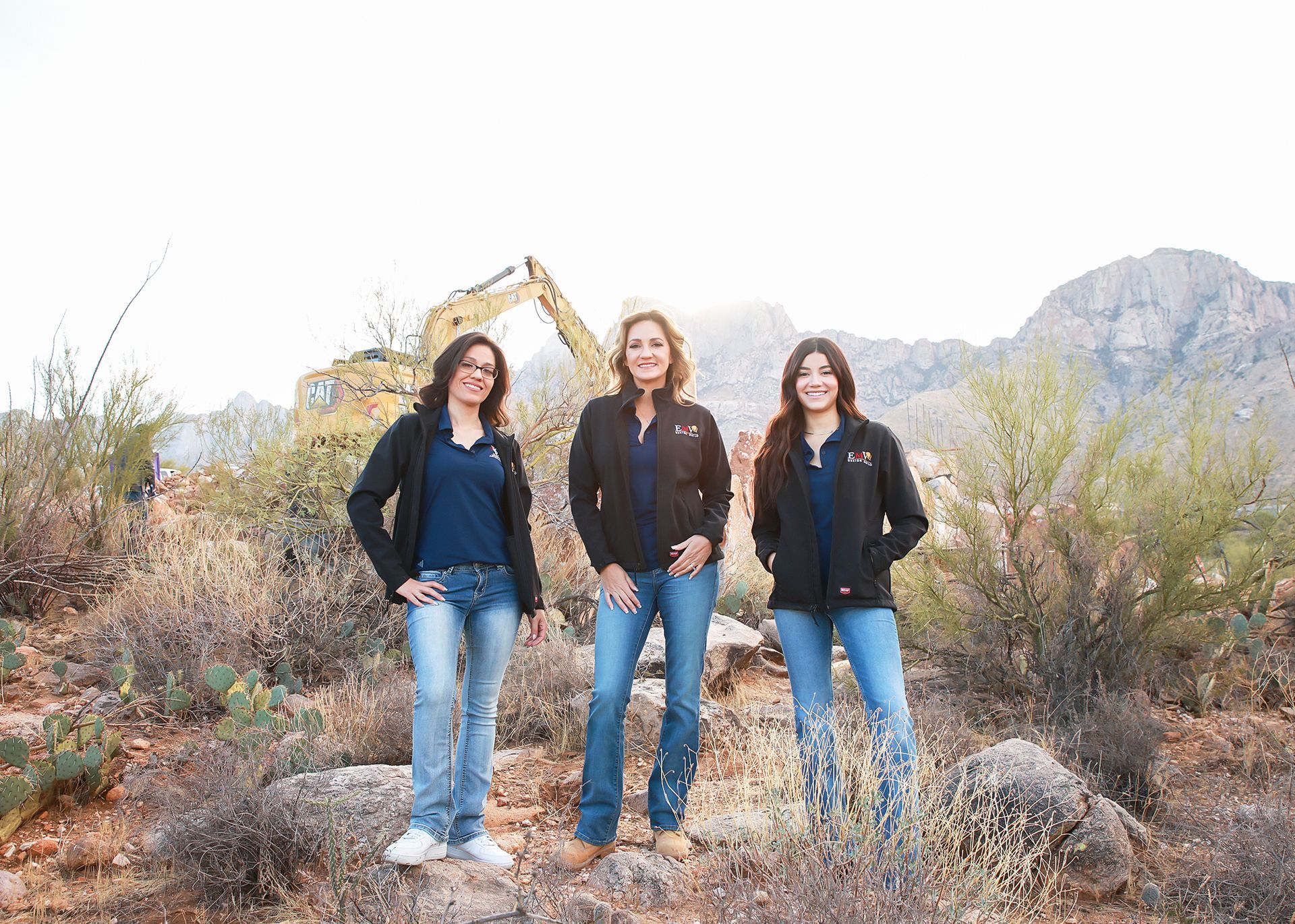 Three women are standing next to each other in the desert.