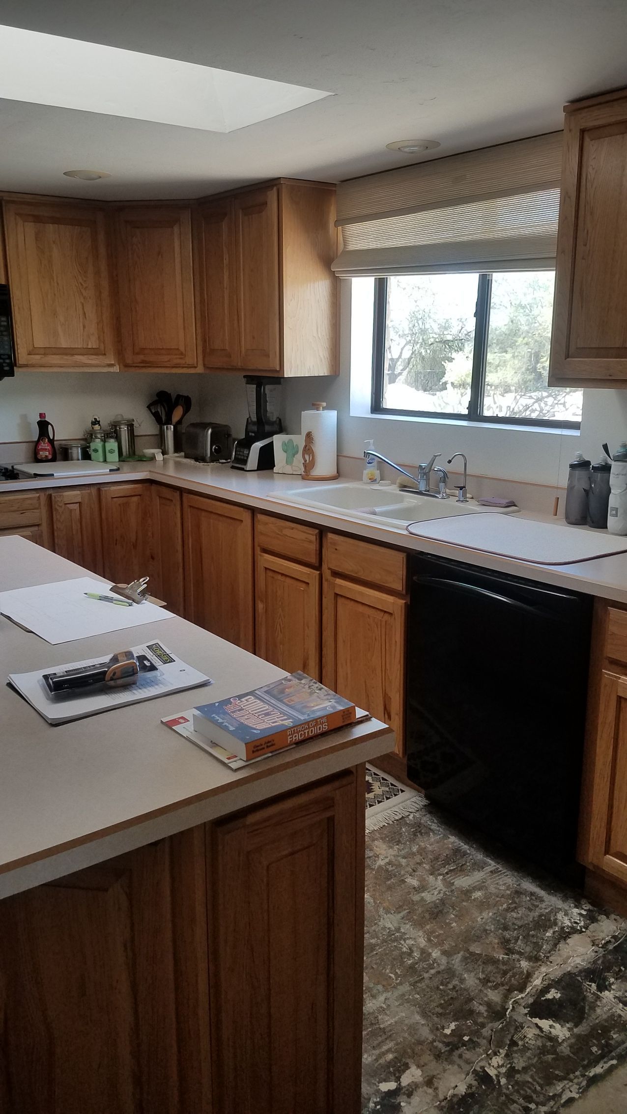 A kitchen with wooden cabinets , a dishwasher , a sink , and a window.