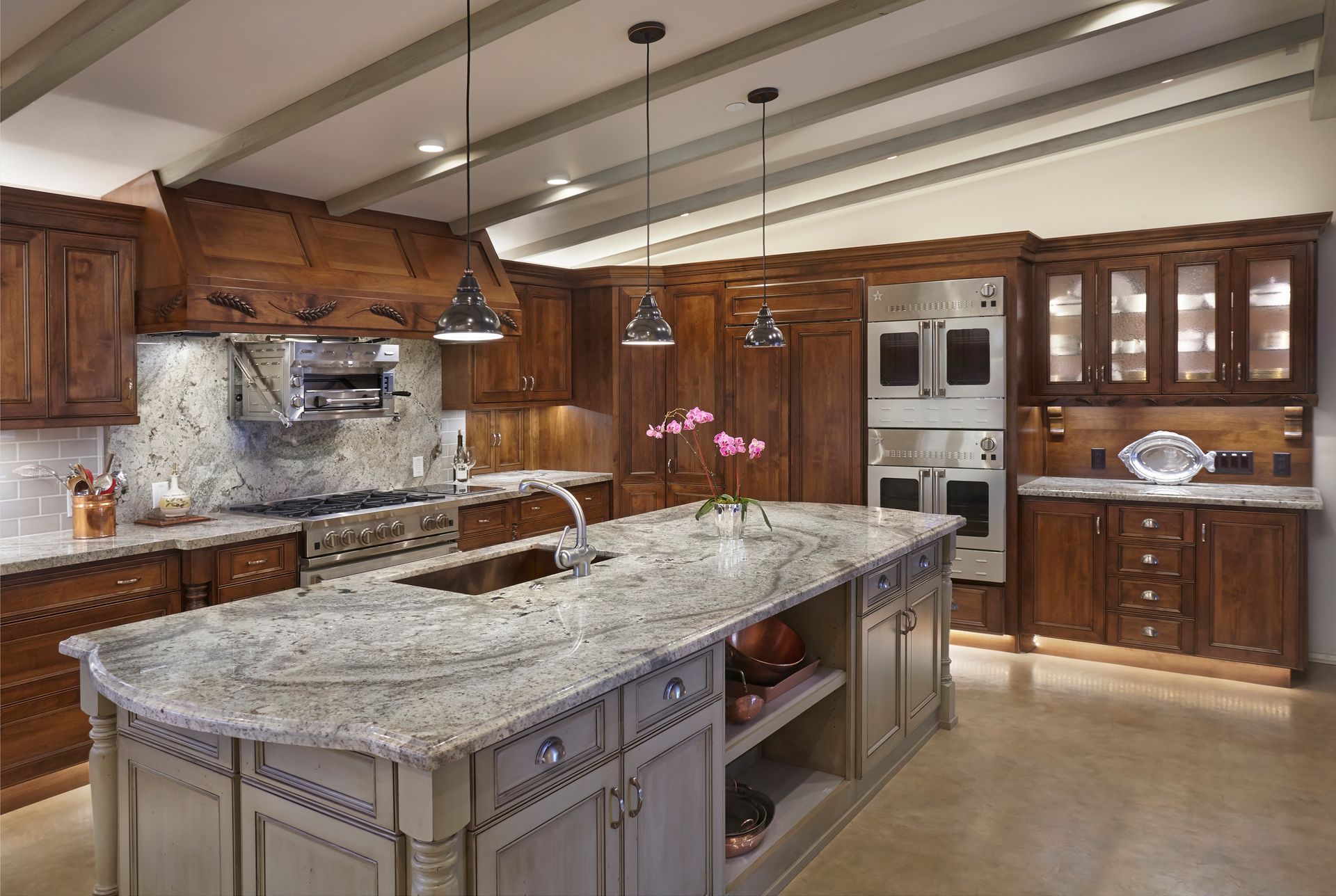 A luxurious kitchen with a large island, dark wood cabinets, and granite countertops.