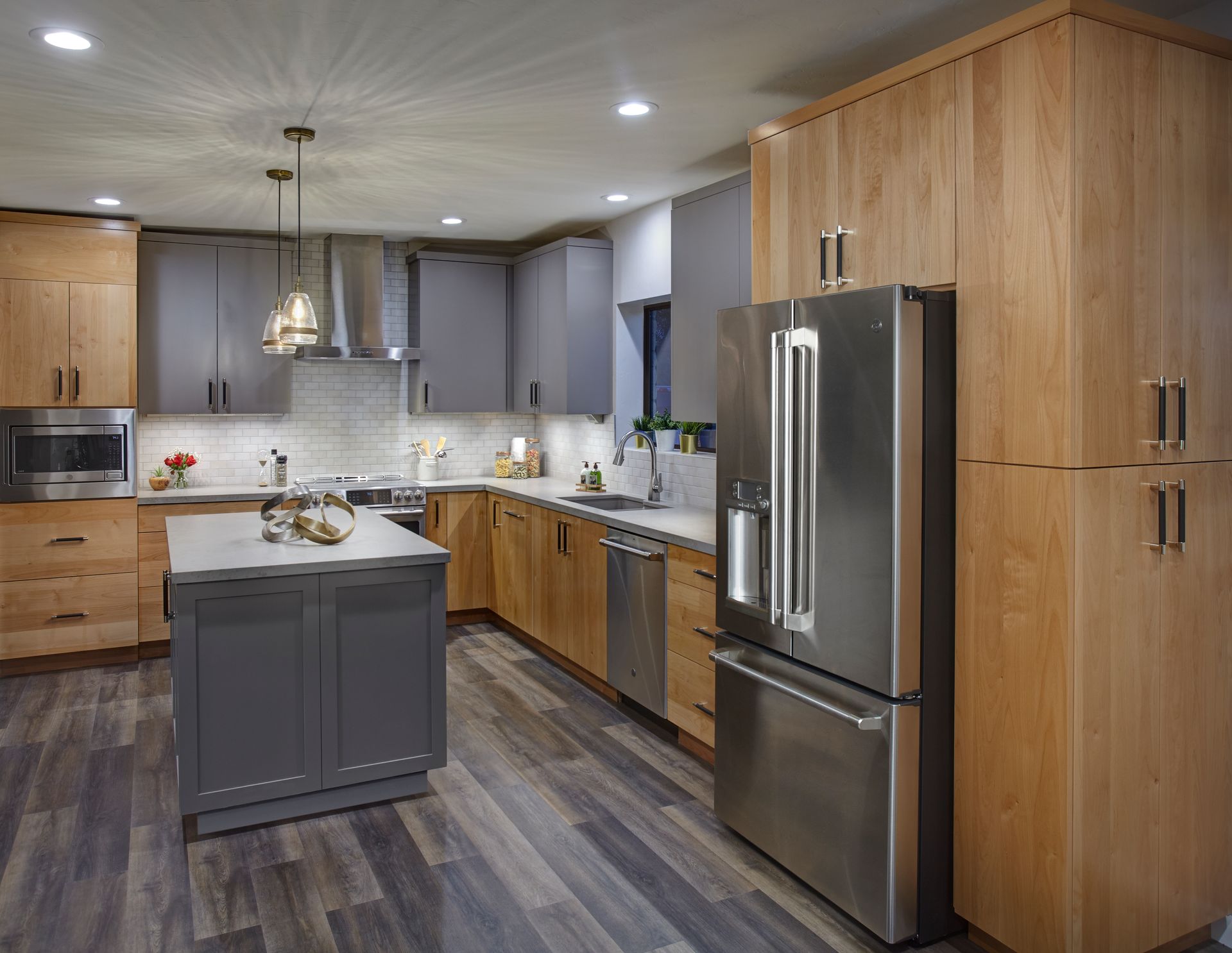 Modern kitchen with gray and wood cabinets, stainless steel appliances, and gray flooring.