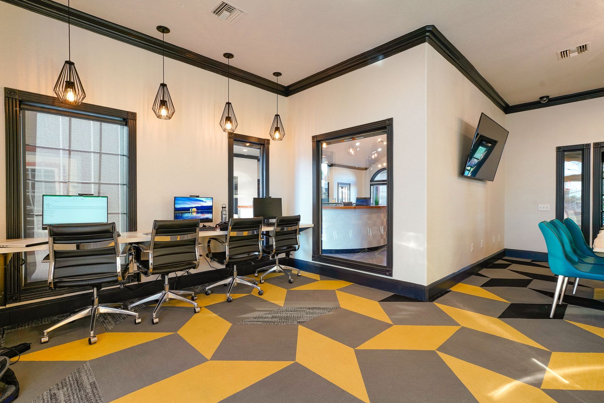 Office space with desks, chairs, and geometric patterned floor.  Black, white, and yellow colors.