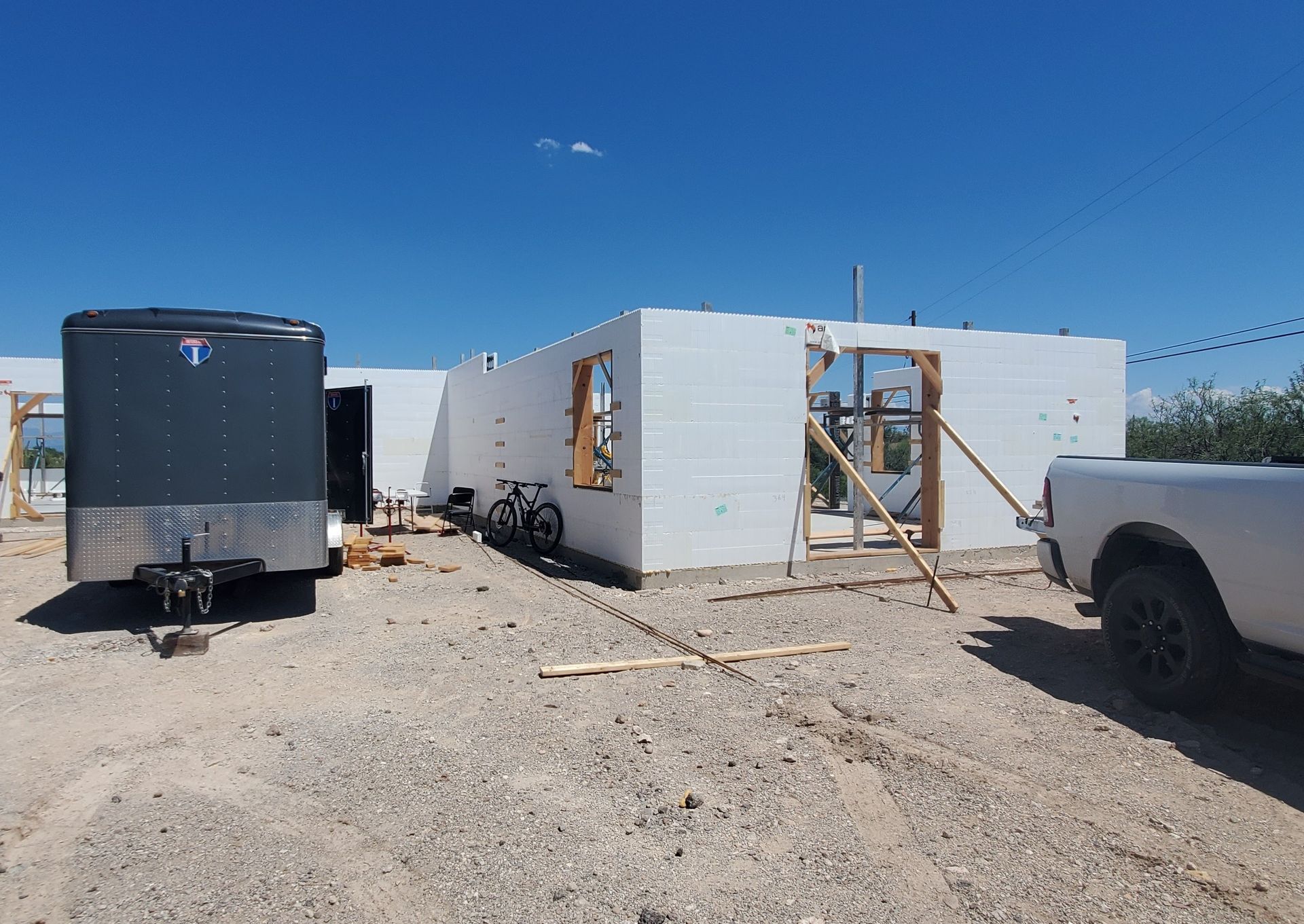 Construction of a one-story building with foam block walls. A trailer and truck are parked nearby.