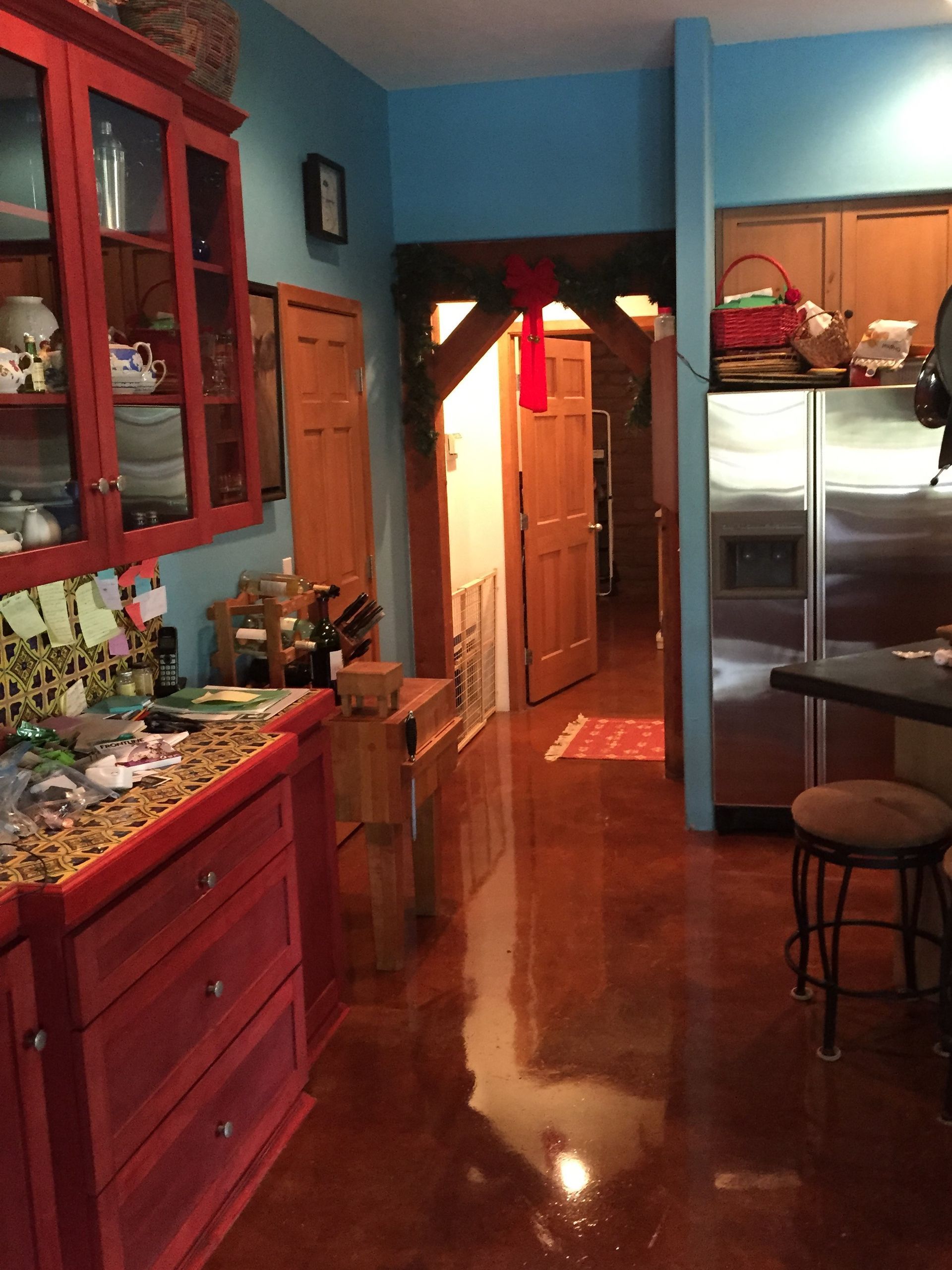 A kitchen with red cabinets and a stainless steel refrigerator