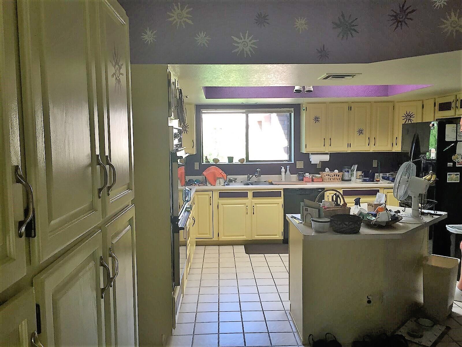 A kitchen with yellow cabinets and a black refrigerator