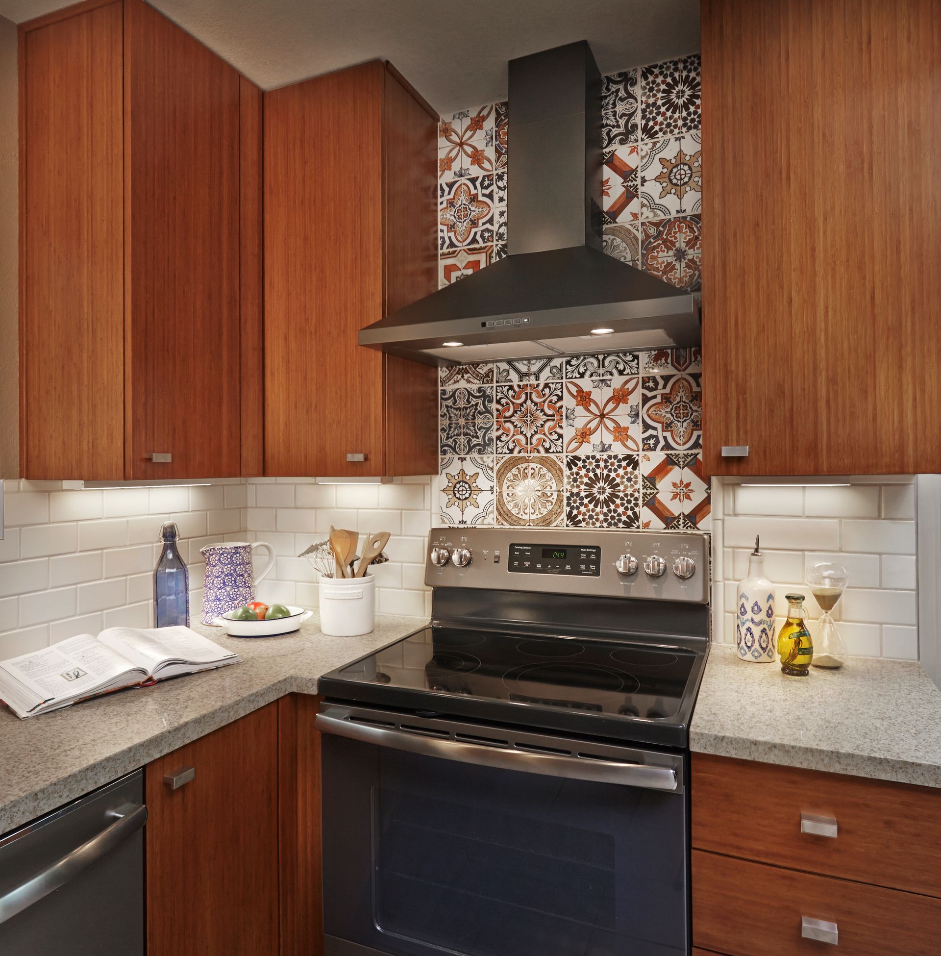 Kitchen with wood cabinets, patterned backsplash, range, and countertops.