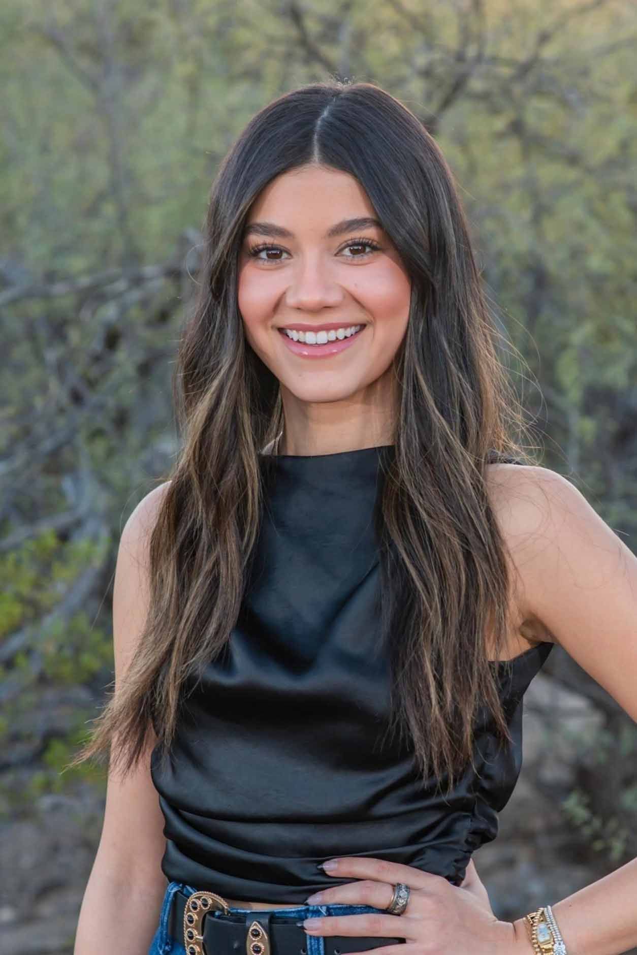 A woman in a black top and jeans is smiling for the camera.