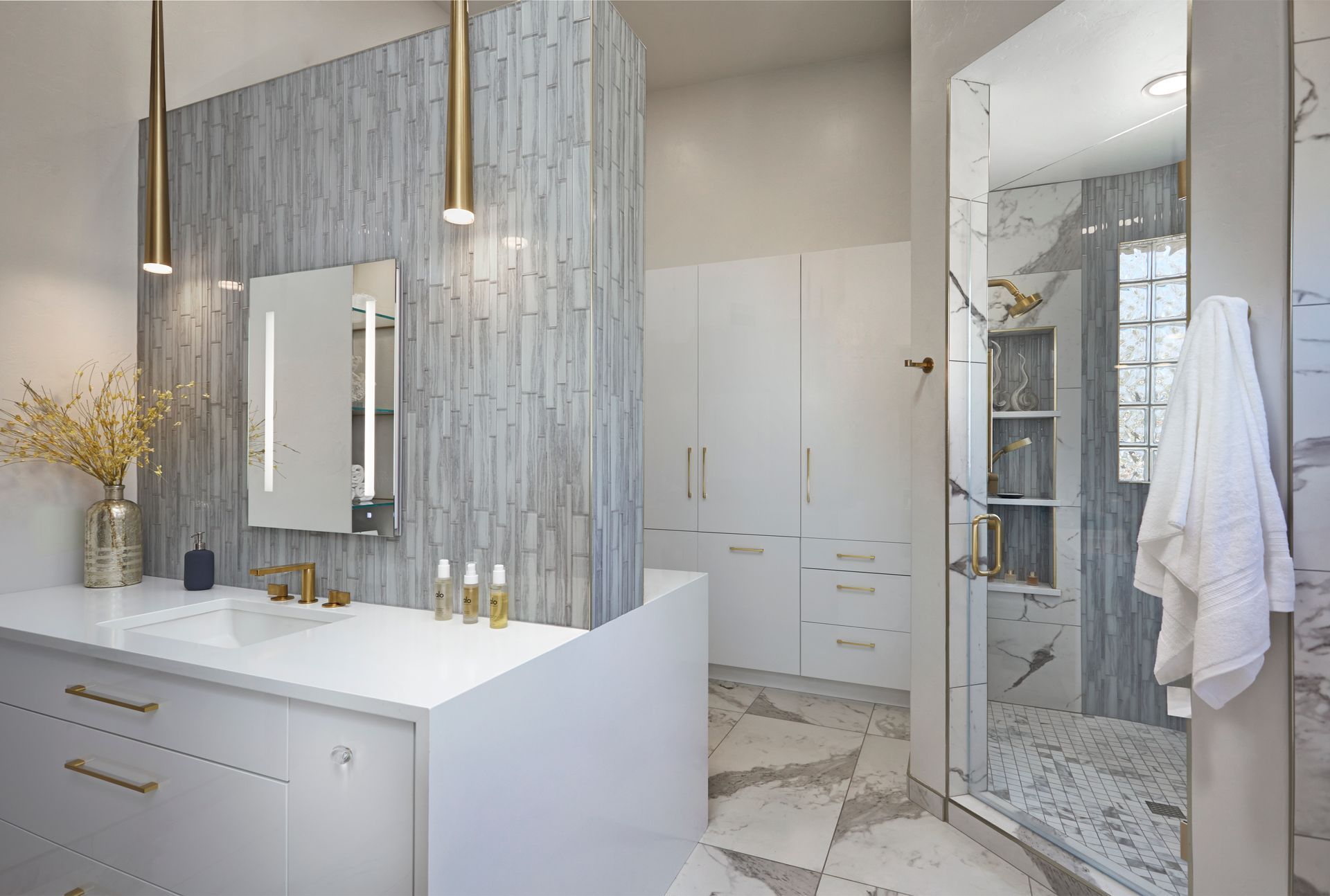 Modern bathroom with stone tile accent wall, vanity, and glass shower.