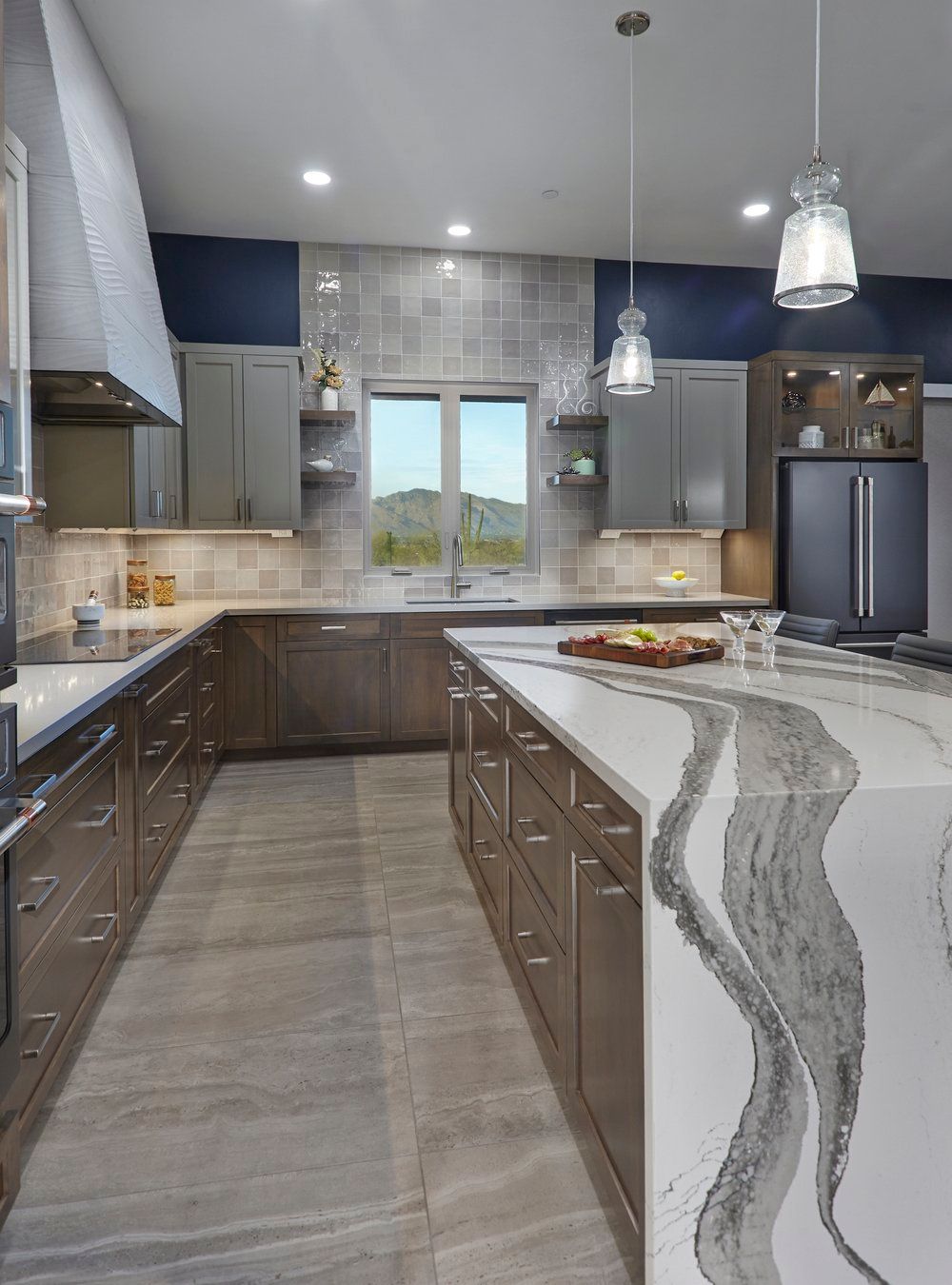 Modern kitchen with gray cabinetry, large island with patterned countertop, and blue accent wall.