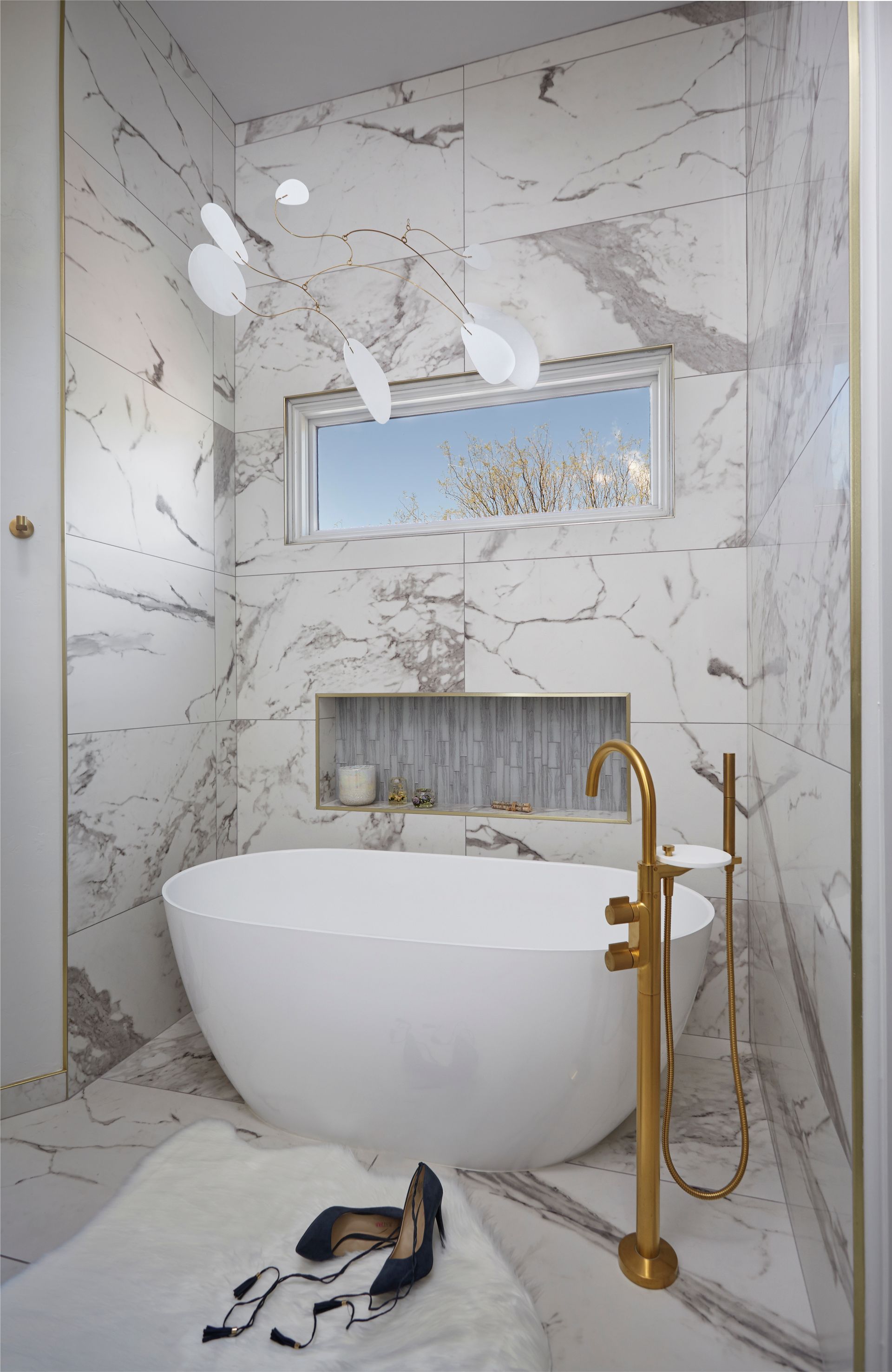 Luxurious bathroom with marble walls, freestanding tub, and gold fixtures.