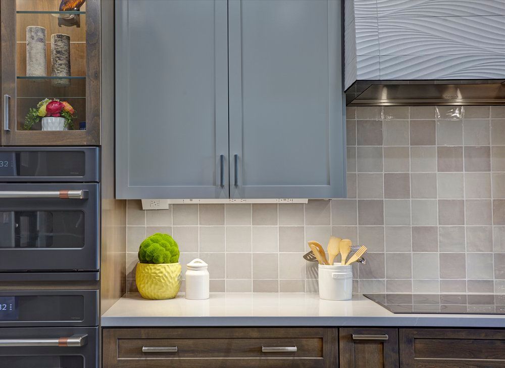 Kitchen with gray cabinets, a white countertop, and tiled backsplash.