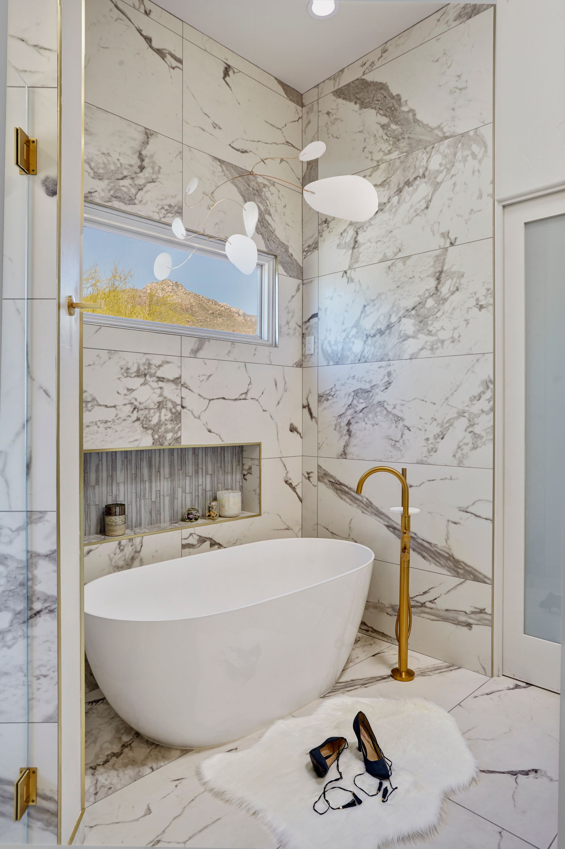 There is a bathtub in the bathroom with marble tiles.