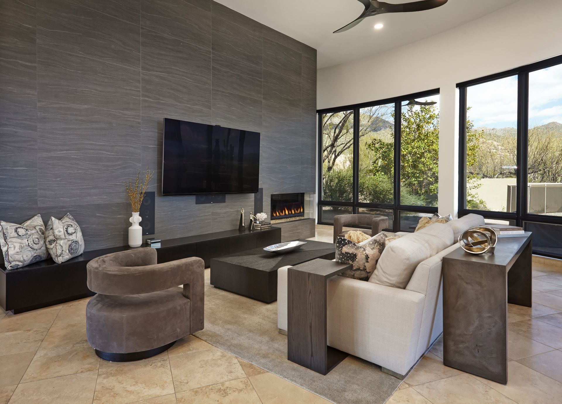 Modern living room with fireplace, TV, and large windows overlooking a scenic view.