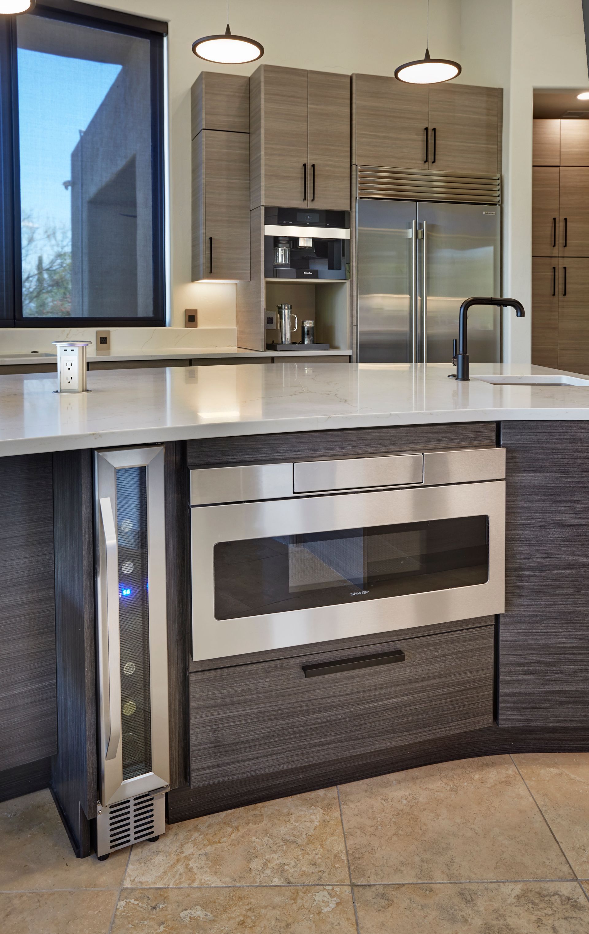 Modern kitchen with a built-in microwave, wine cooler, and stainless steel refrigerator.