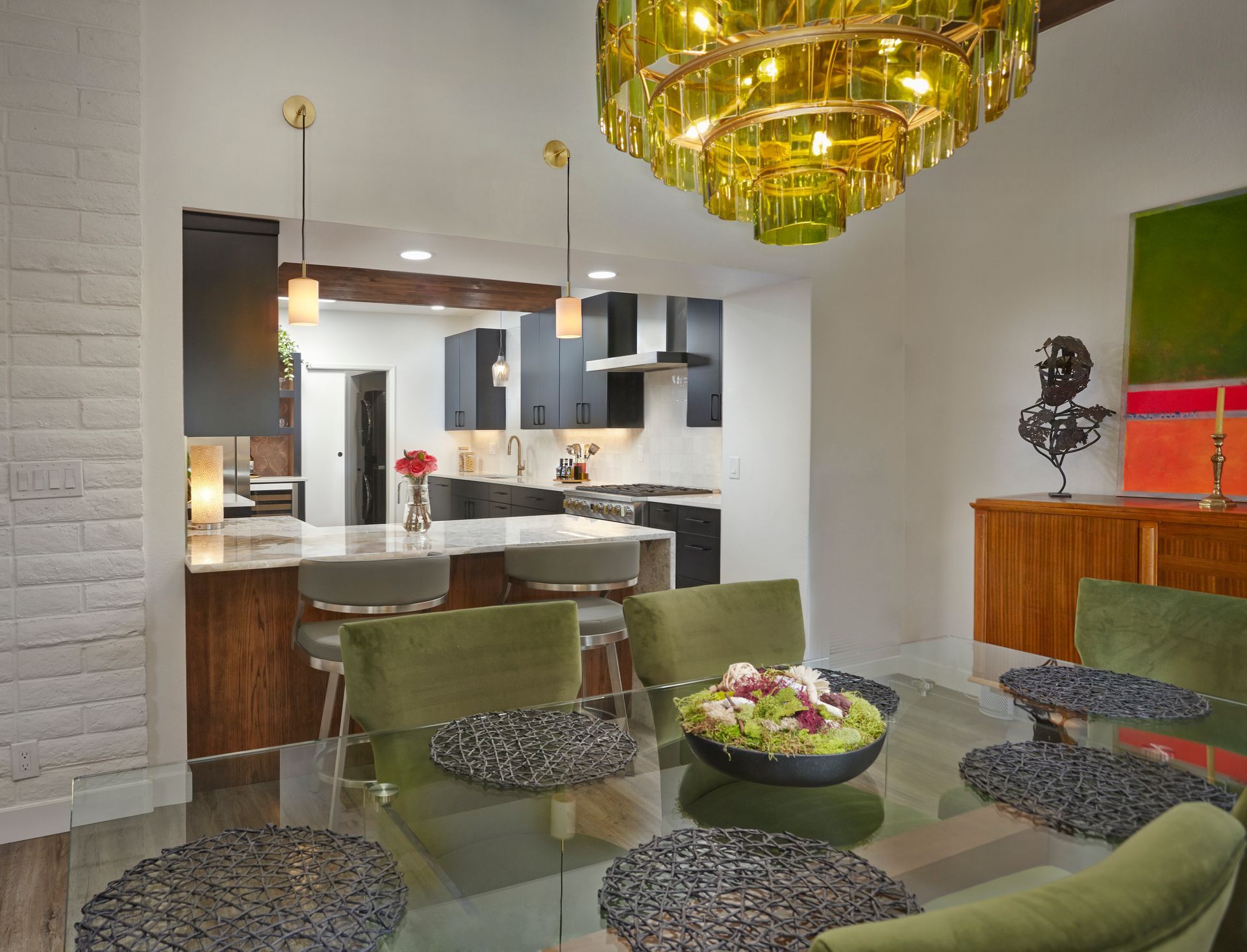 A dining room with a glass table and green chairs