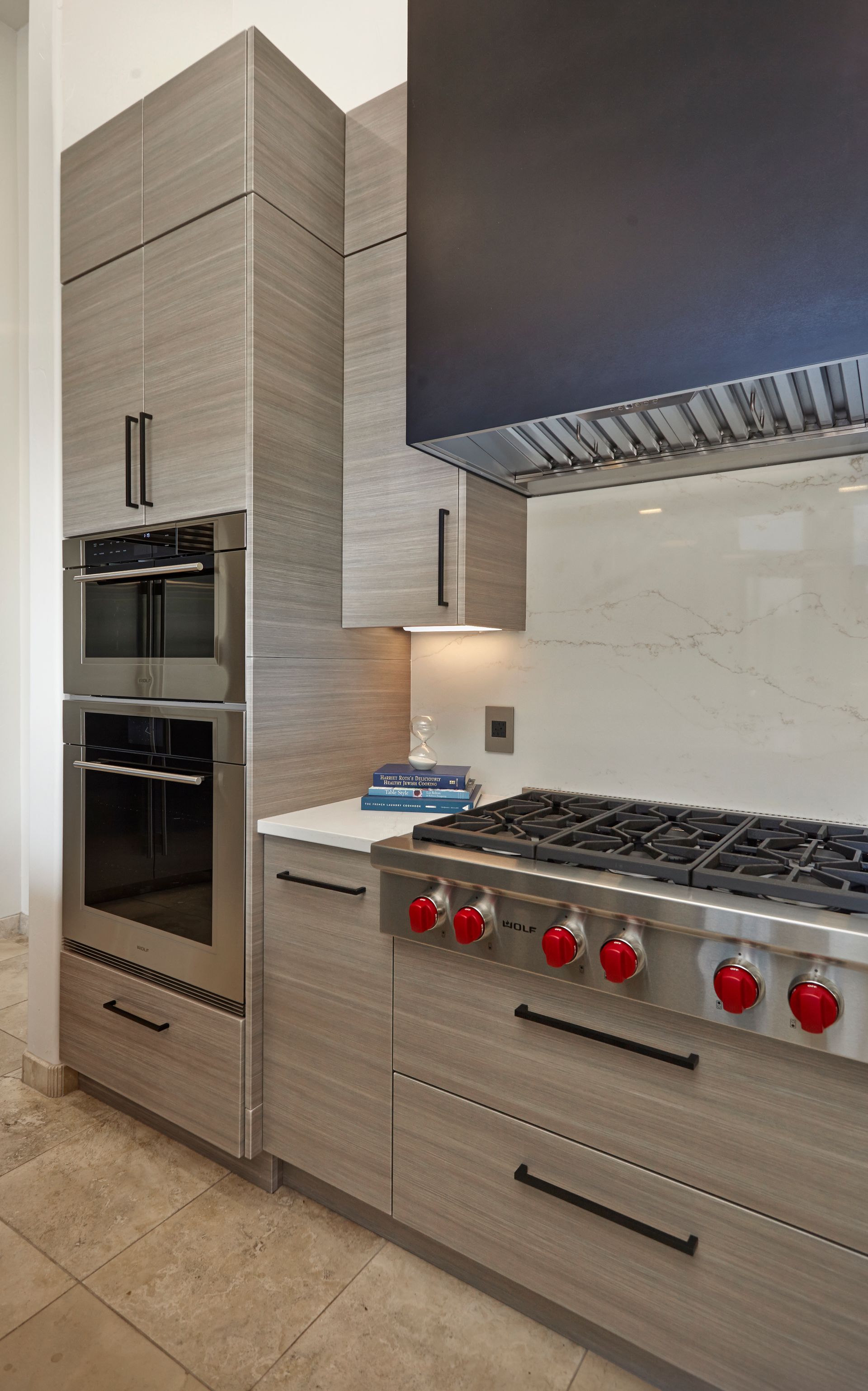 Modern kitchen with gray cabinets, stainless steel oven, and Wolf range.