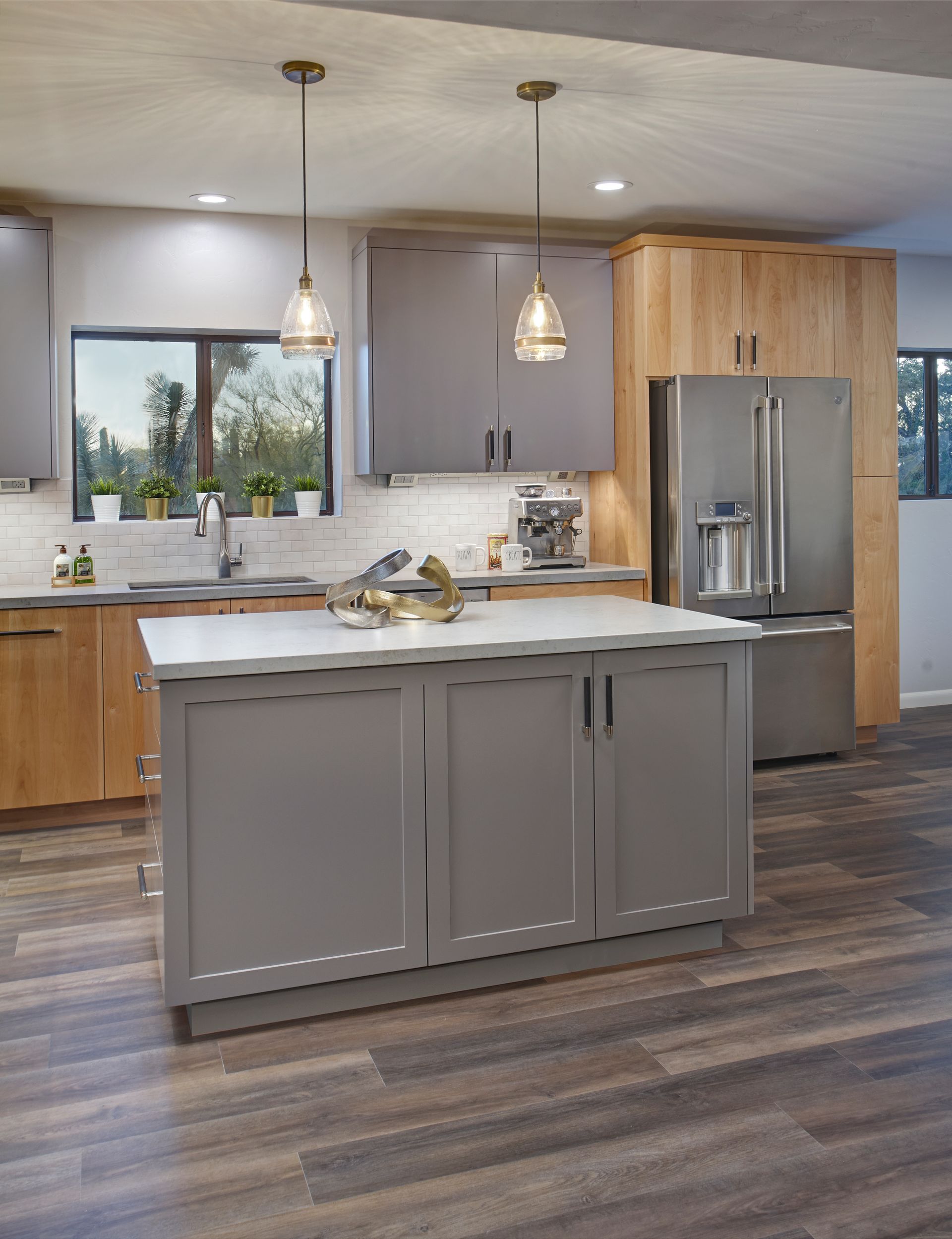 Kitchen with gray island and cabinets, stainless steel refrigerator, and wooden accents.
