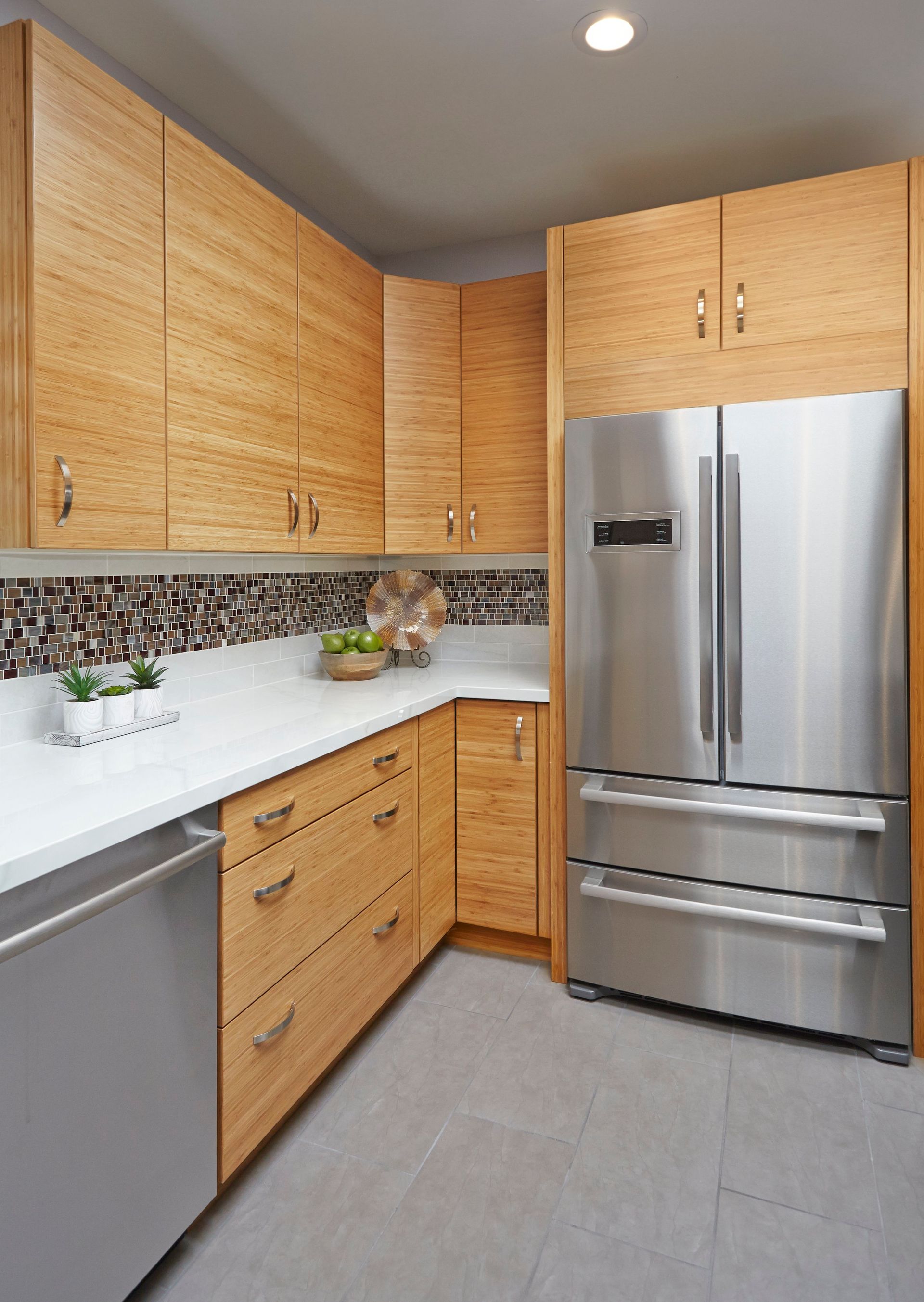 Kitchen with light wood cabinets, stainless steel appliances, white countertop, and mosaic backsplash.