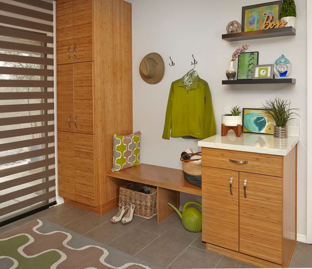 Mudroom with wood cabinetry, bench, and shelves, featuring a window and rug with a green accent.