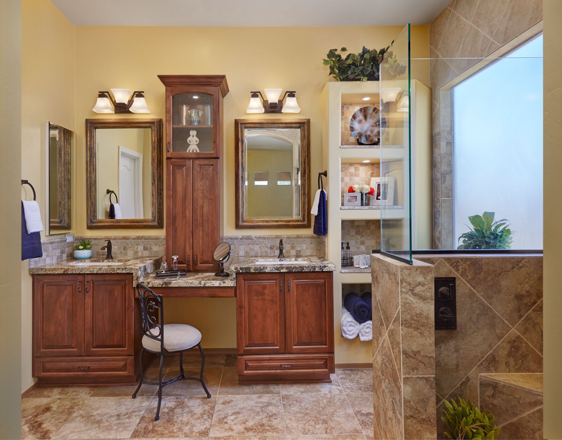 Bathroom with brown cabinets, cream tile floor, mirrors, and a glass shower.