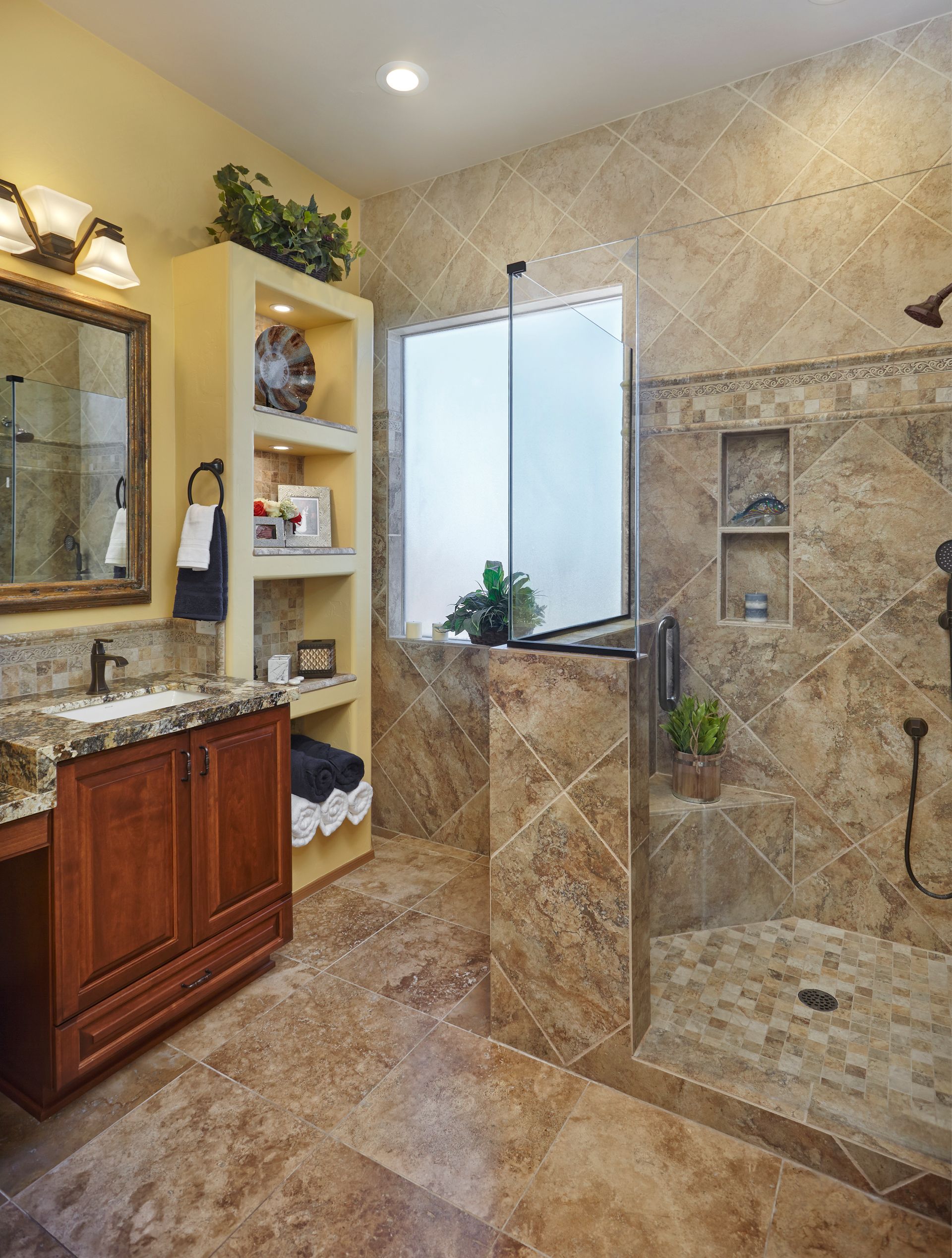 Bathroom with marble tile, dark wood vanity, built-in shelving, and walk-in shower.