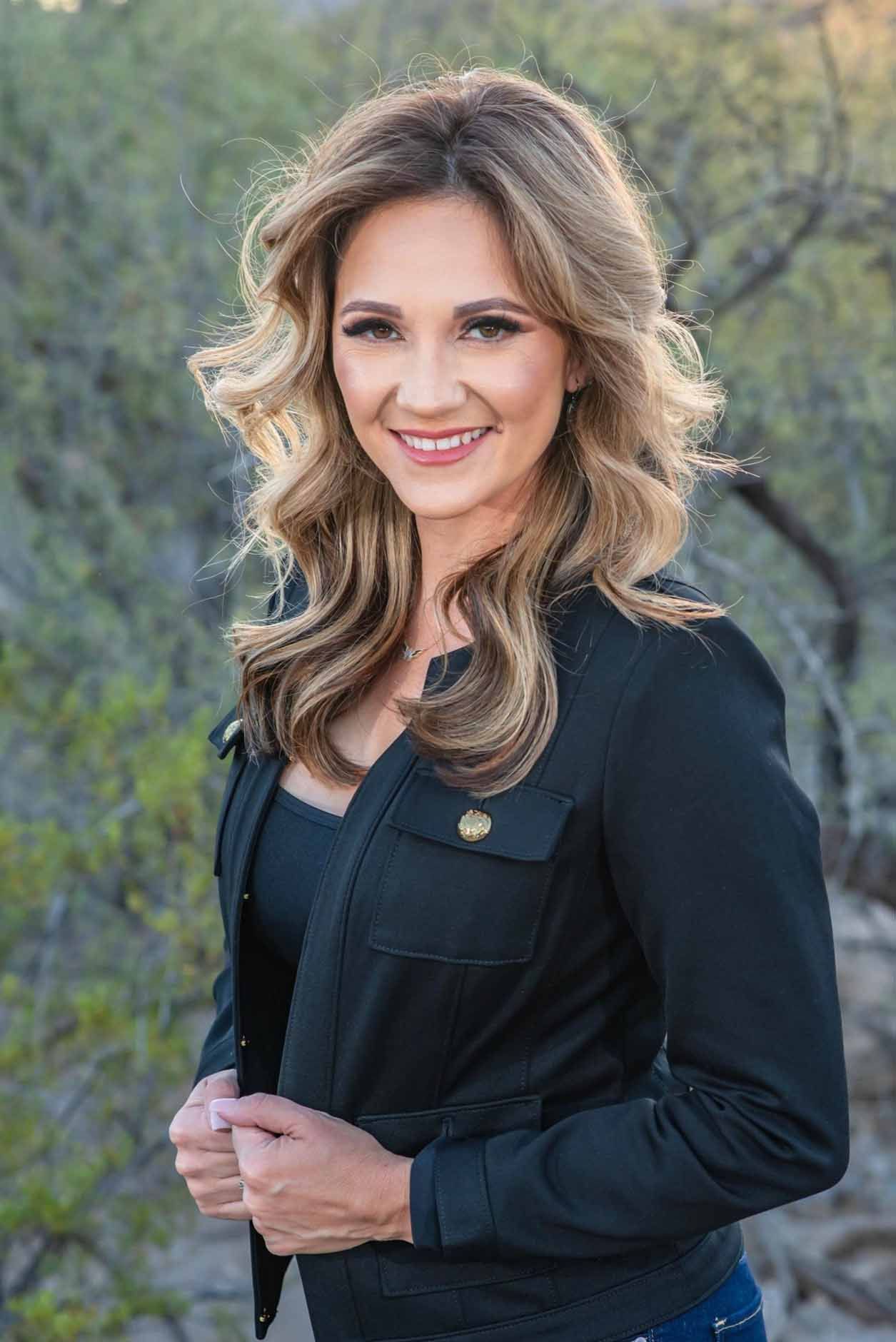 The woman is wearing a black jacket and smiling for the camera.