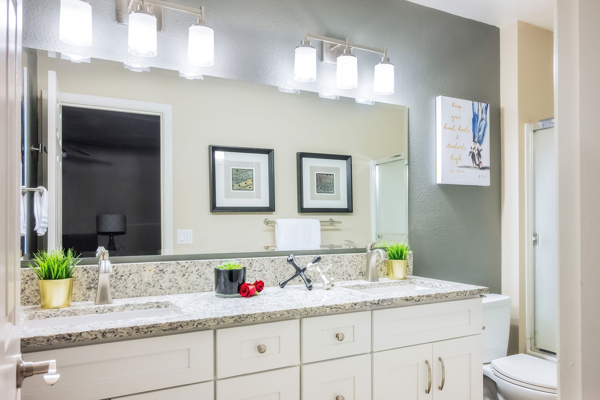 Bathroom with a double vanity, large mirror, and overhead lights. Gray and white color scheme.