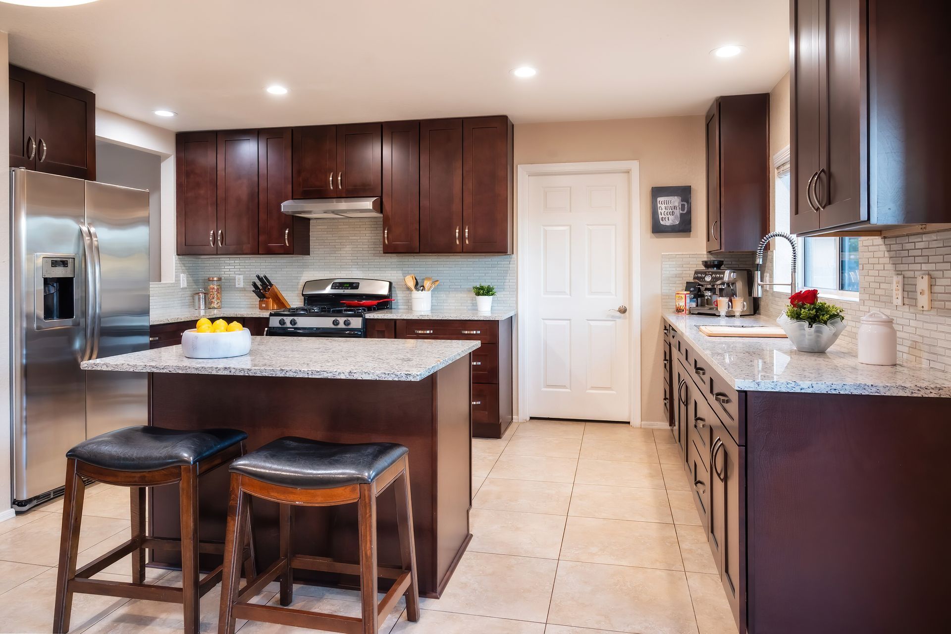 Modern kitchen with dark brown cabinets, granite countertops, and stainless steel appliances.