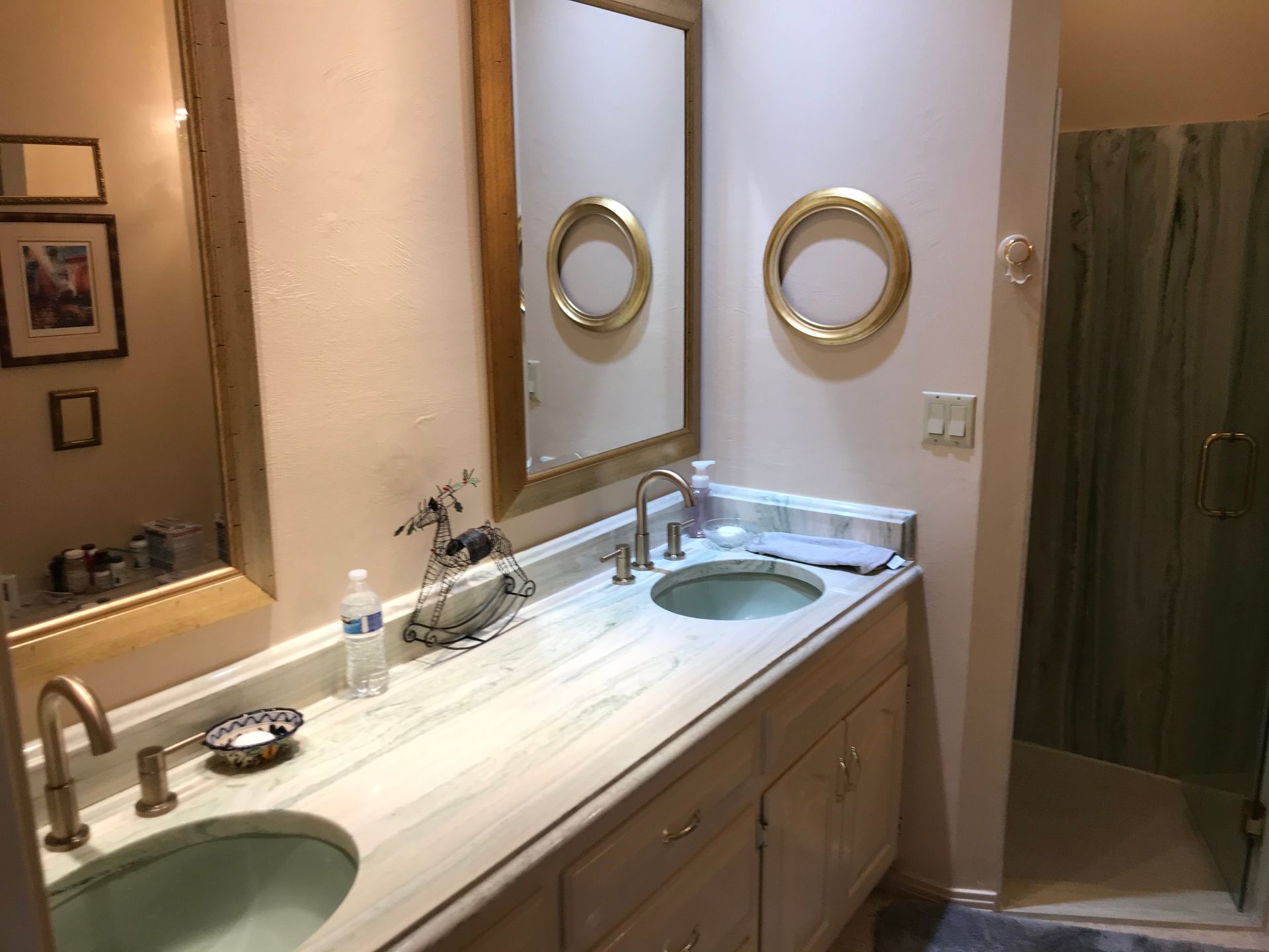 A bathroom with two sinks , two mirrors and a walk in shower.