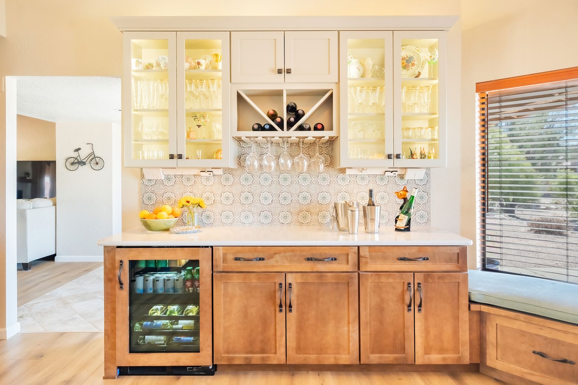 Built-in bar with light wood cabinets, glass display cabinets, and a mosaic backsplash.