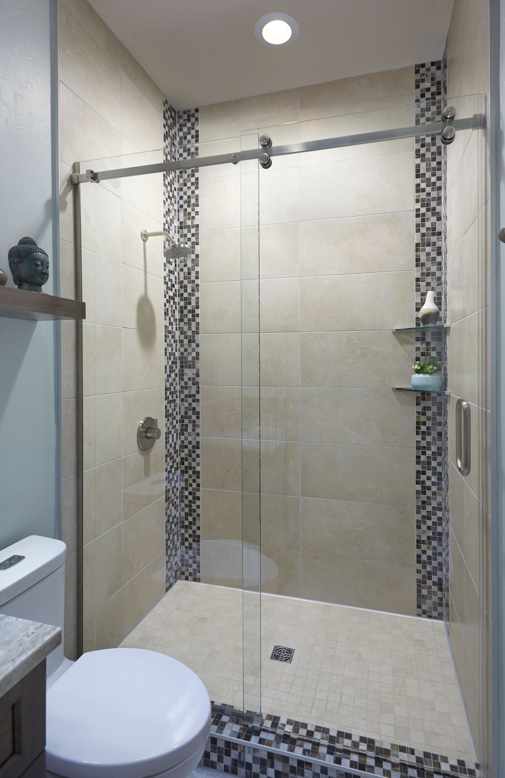 Small modern bathroom with tiled shower, sliding glass door, and toilet.
