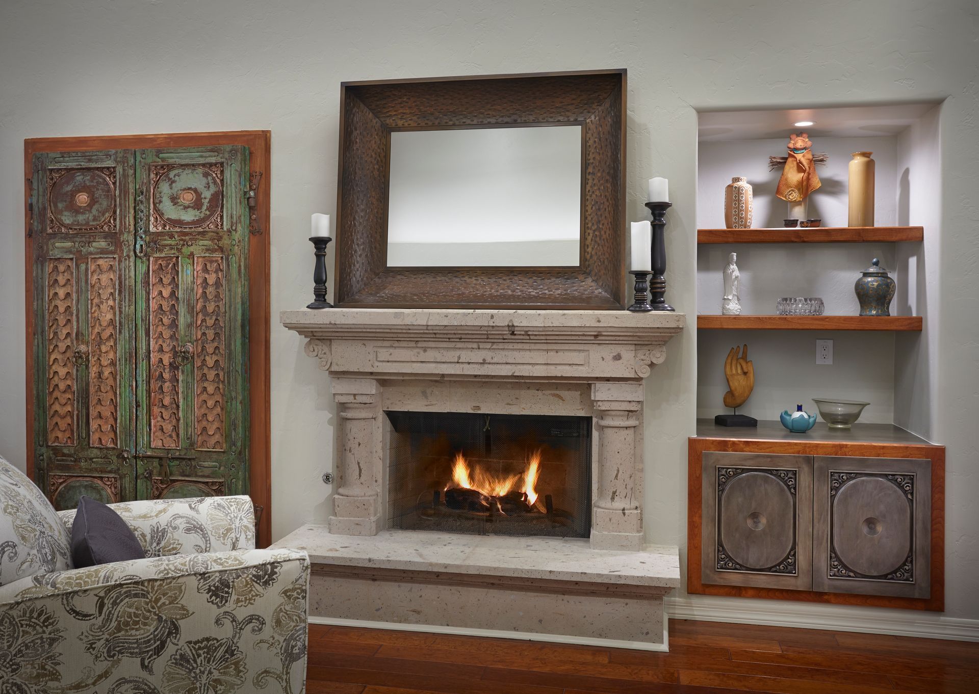 Fireplace with mirror, built-in shelving, and an antique door. A cozy living room with a lit fire.