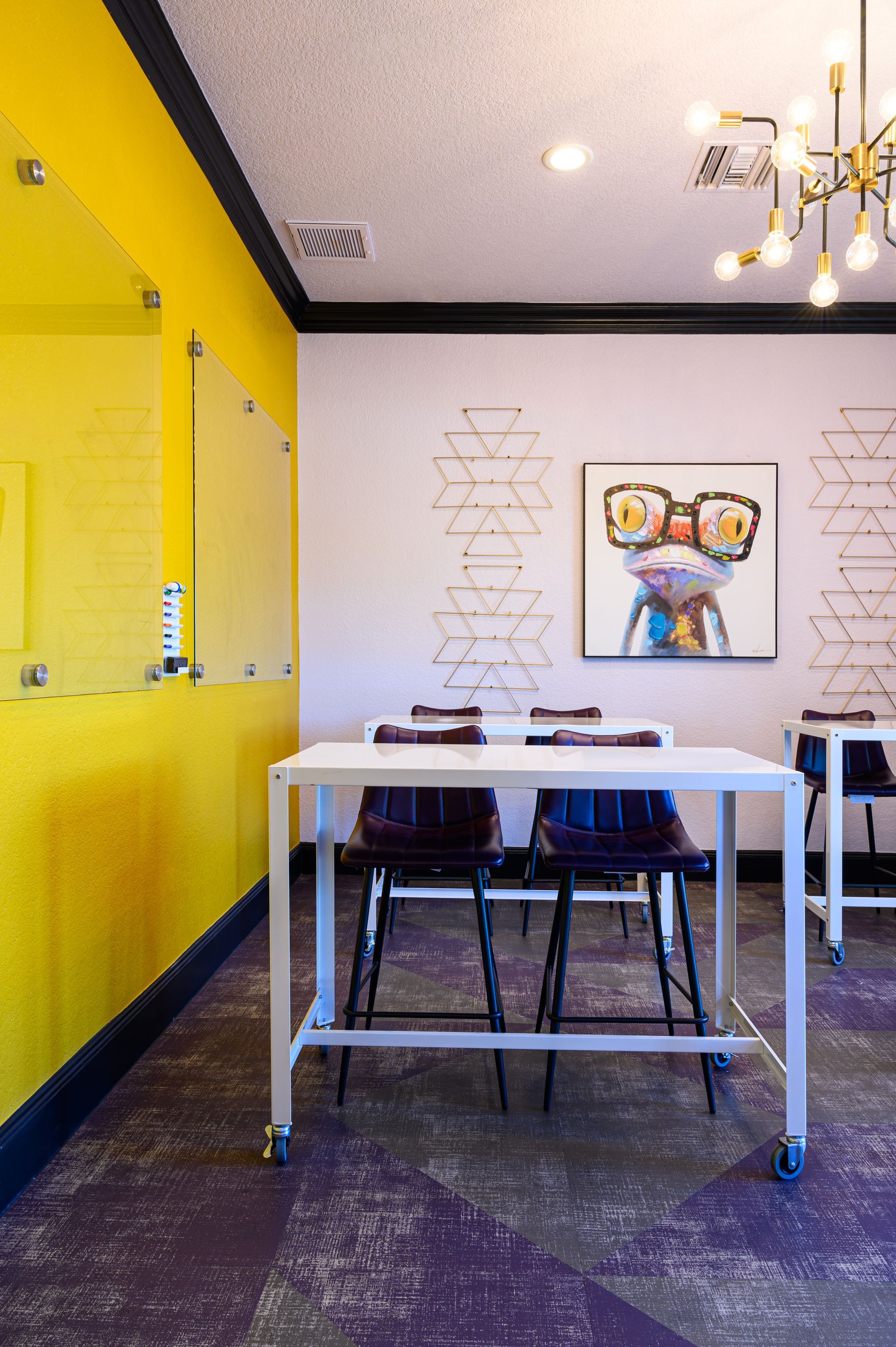 Interior of an optometry office with yellow and white walls, tables, and a piece of art.