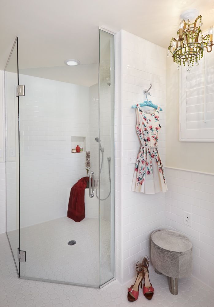 A bathroom with a shower and a dress hanging on the wall