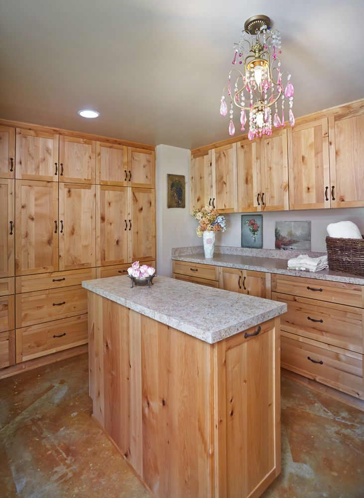 Laundry room with light wood cabinets, an island, and a chandelier.