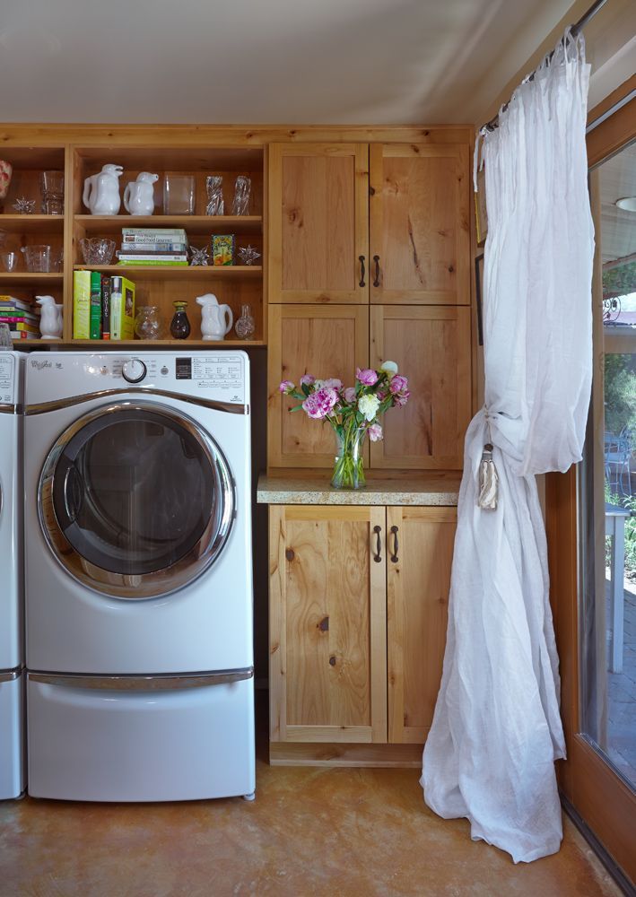 Laundry room with washer, cabinetry, and sheer curtain.