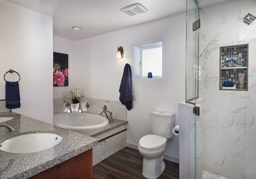 Bathroom with white walls, tub, toilet, granite countertop, and marble shower.