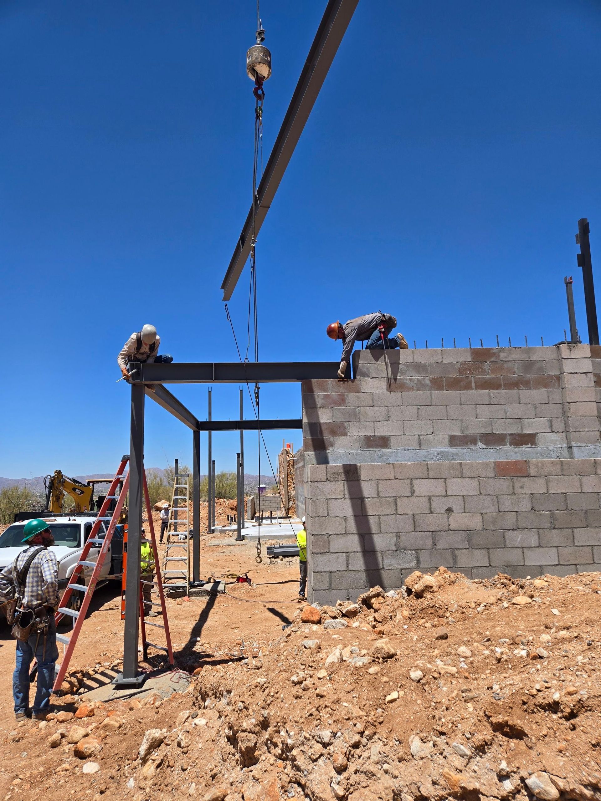 Construction workers installing a steel beam on a building frame with a crane on a sunny day.