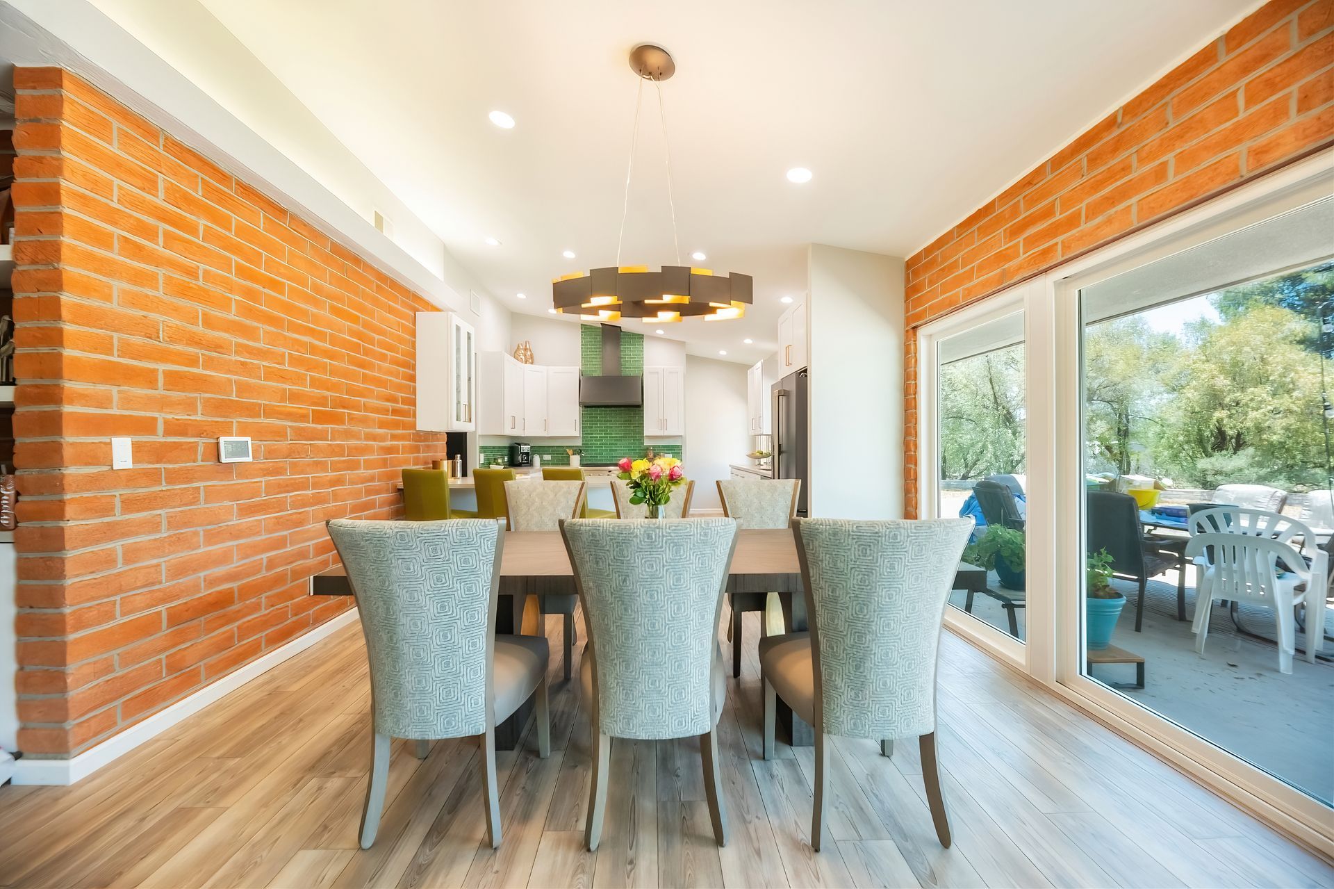 Dining room with brick wall, table, patterned chairs, and a sliding glass door to a patio.