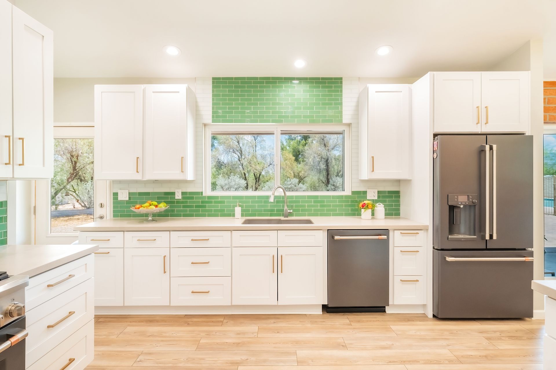 White kitchen with green tile backsplash, stainless steel appliances, and wood floors.