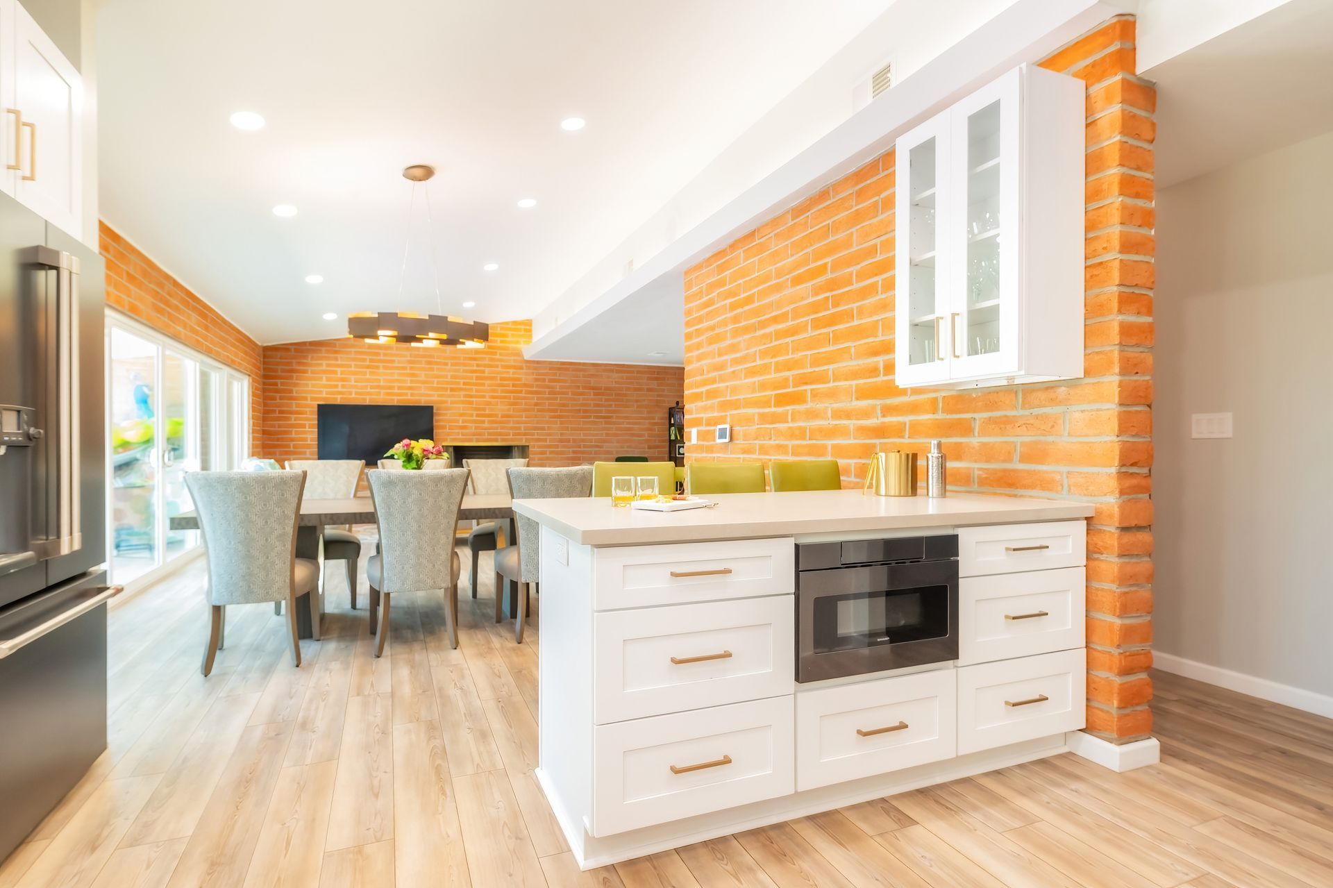 Open-concept kitchen with brick accent wall, white cabinets, and dining table set.