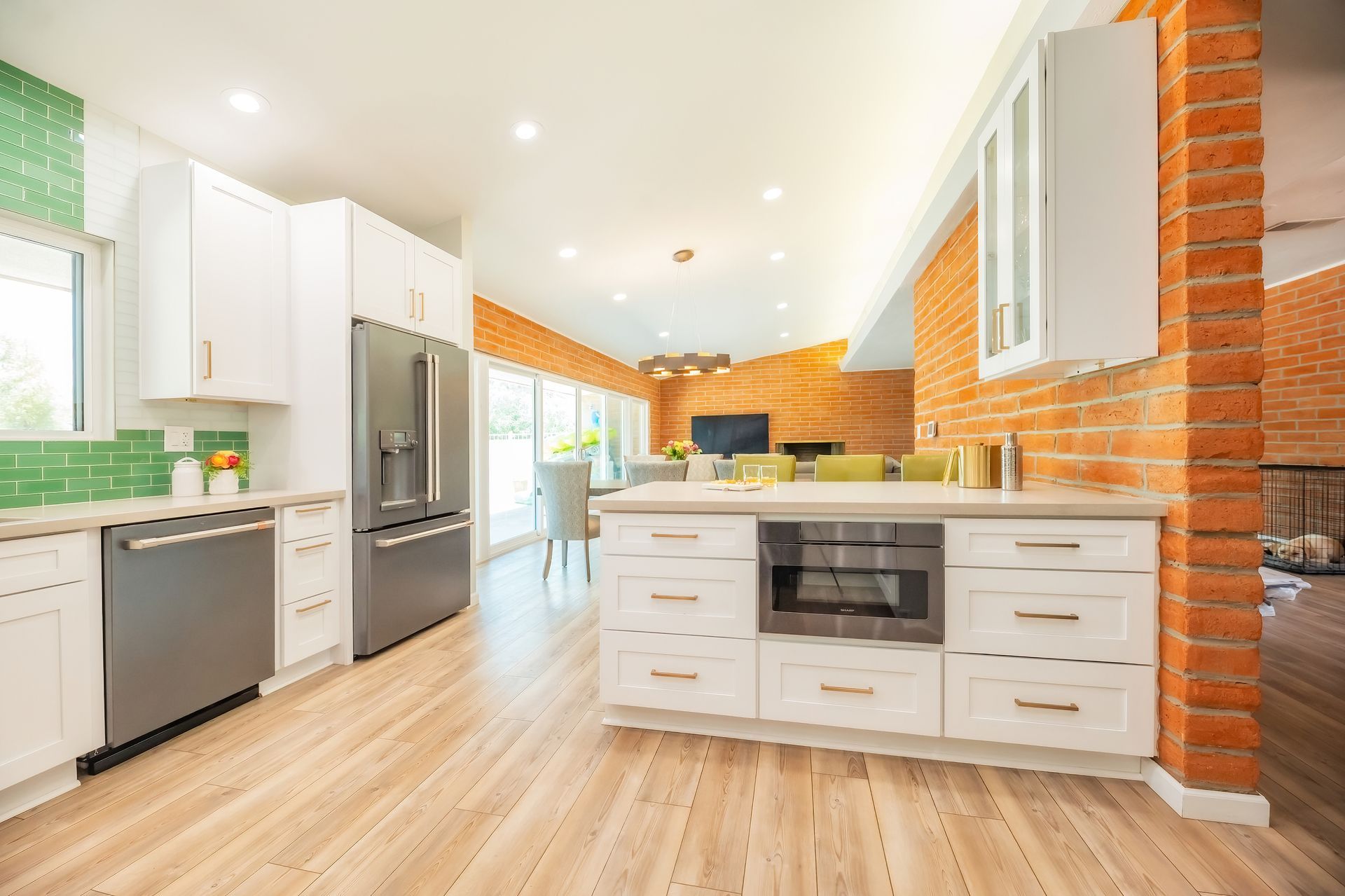 Modern kitchen with white cabinets, stainless steel appliances, and brick accent wall.