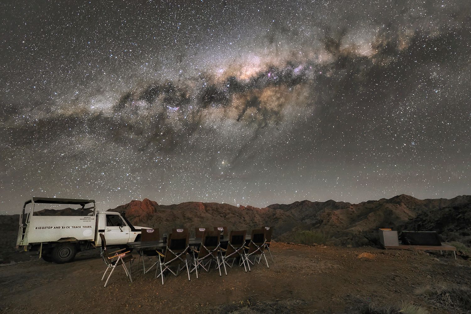 A camp kitchen at the Ridgetop Sleepout Experience under a starry night sky. 